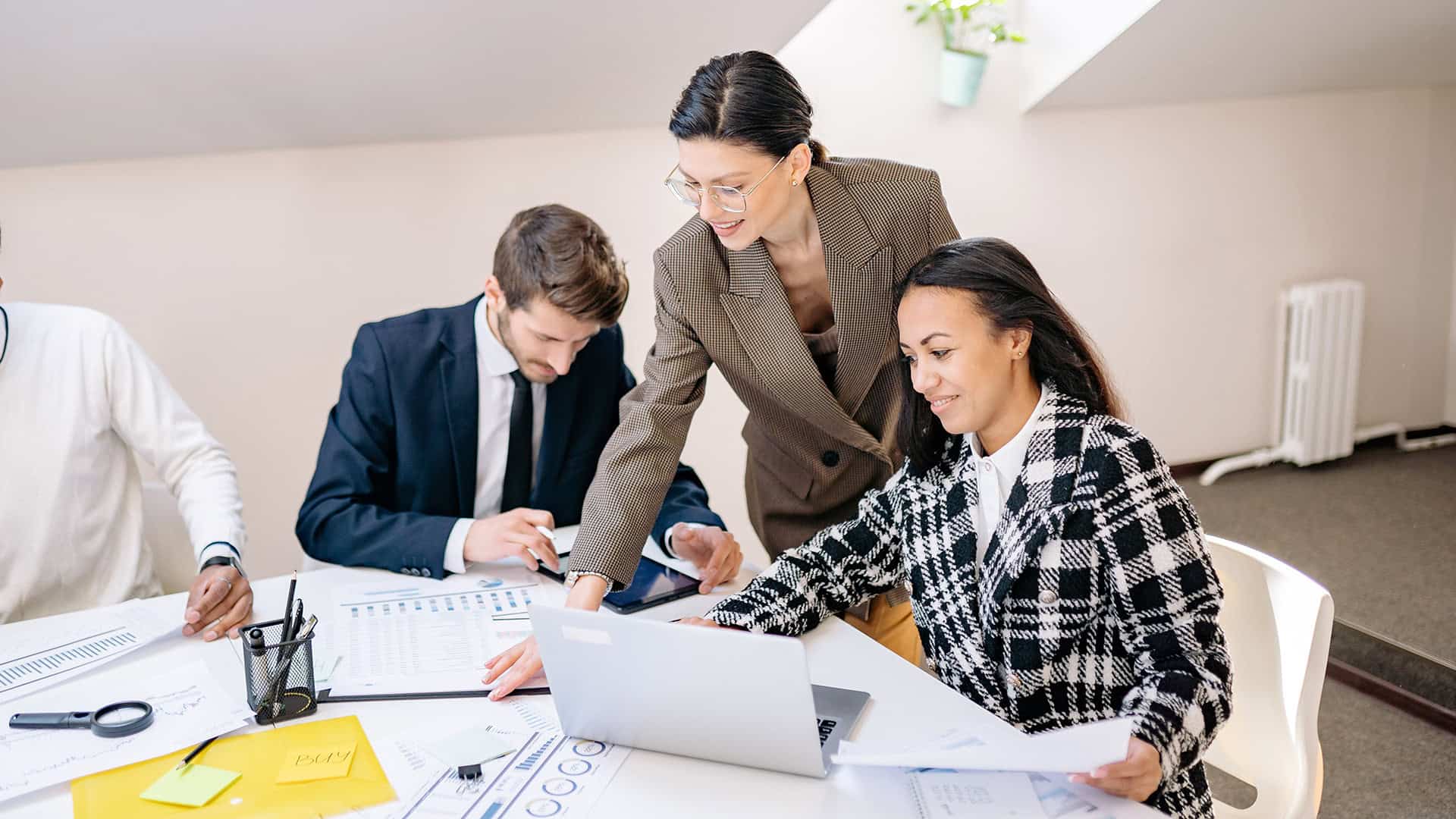 Business team collaborating on a laptop in a modern office setting.